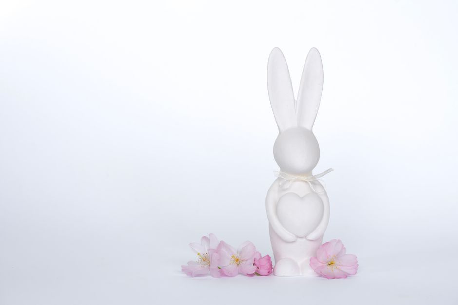 Charming white rabbit ornament with heart symbol, surrounded by sakura blossoms on a white background.