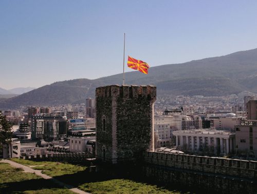 Free Historic stone tower with the Macedonian flag overlooks Skopje skyline. Stock Photo