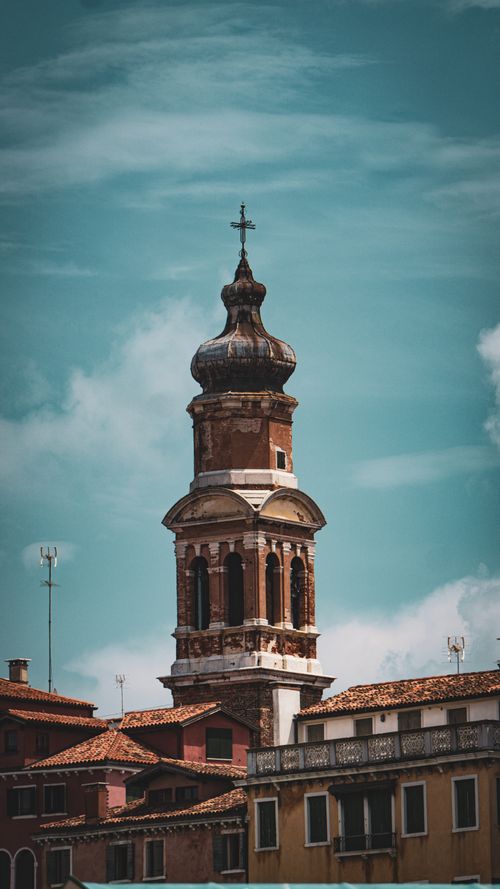 Free Scenic view of a historic bell tower amidst Venetian architecture under a bright blue sky. Stock Photo