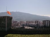 Scenic view of Skopje cityscape featuring the Macedonian flag and mountainous backdrop.