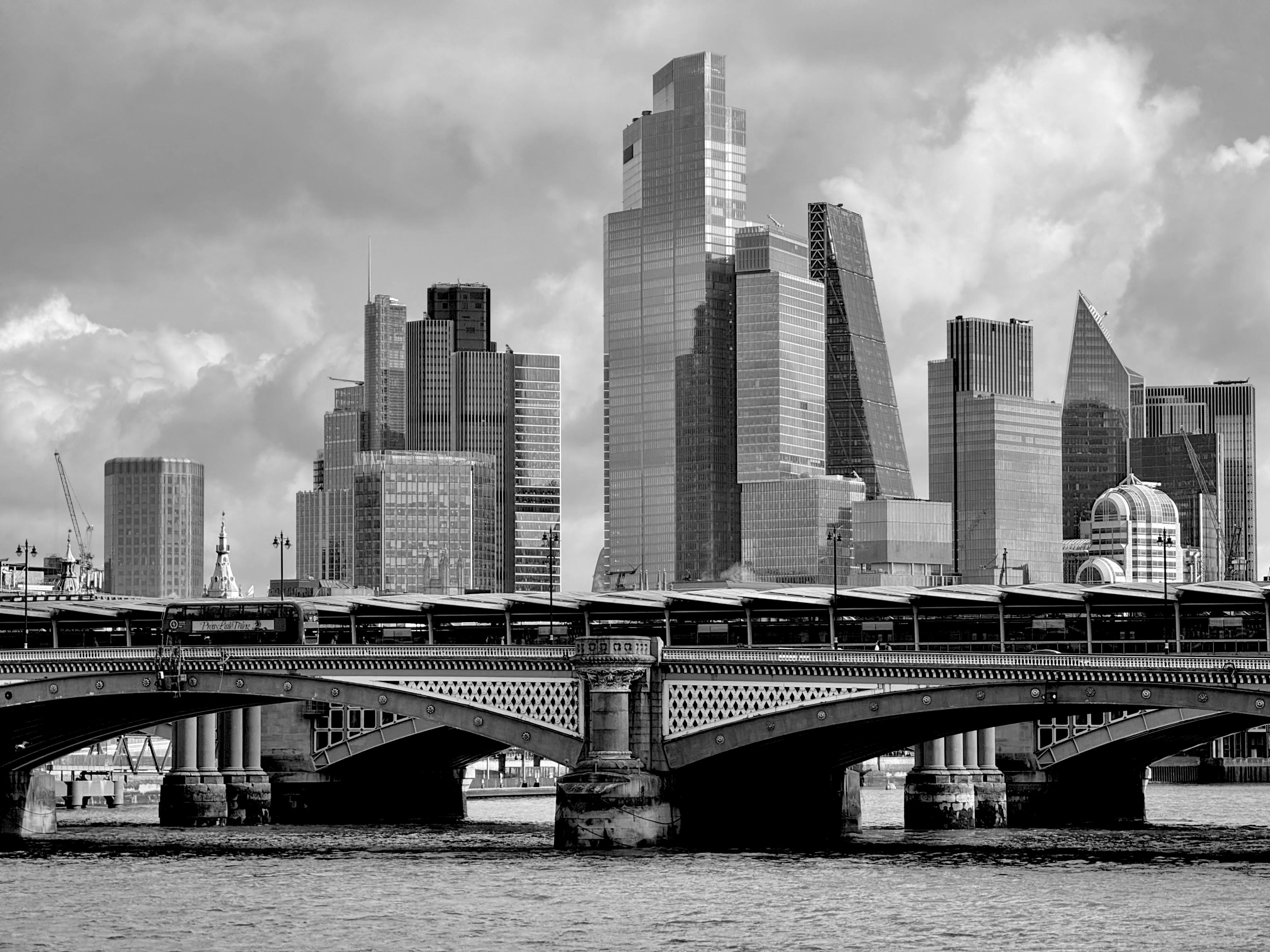Dramatic black and white skyline with a bridge and skyscrapers.