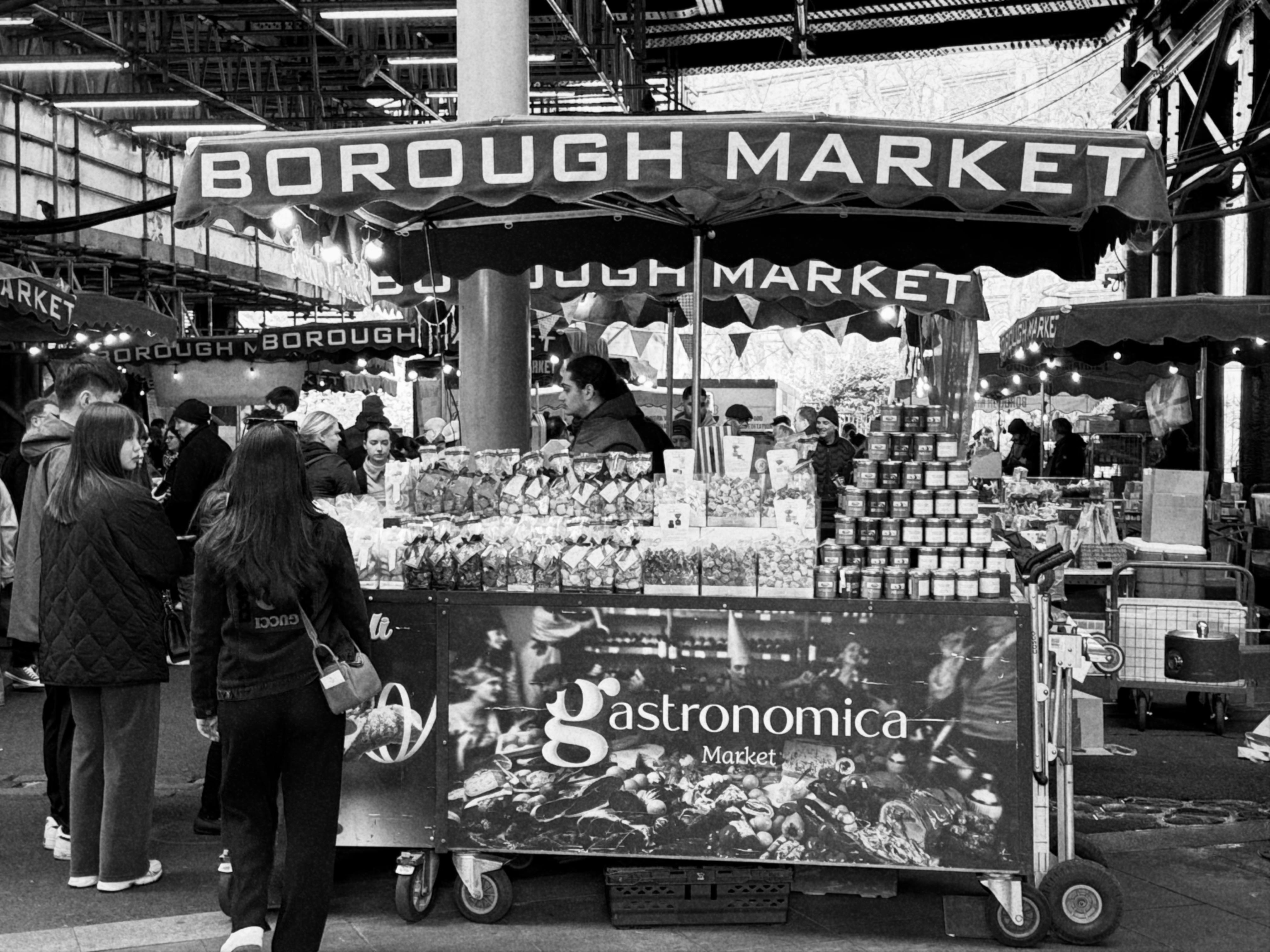 Black and white image of Borough Market's vibrant atmosphere with shoppers and stalls.