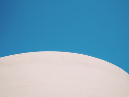 Free Minimalist architecture with a smooth white curve against a vivid blue sky Stock Photo