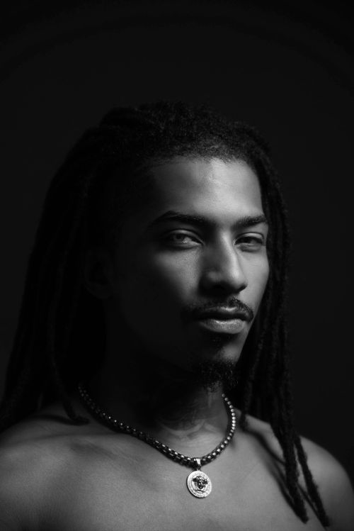 Free Artistic black and white portrait featuring a young man with dreadlocks and necklace. Stock Photo