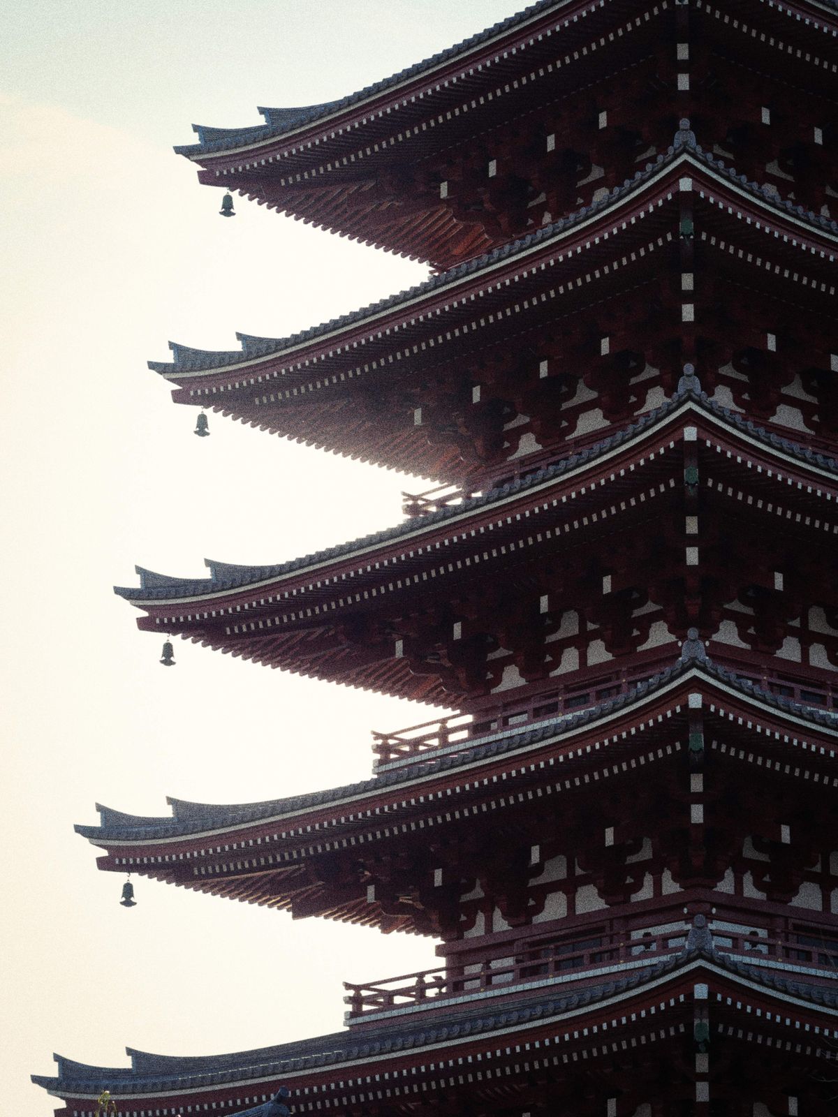 A tall multi-storied vermillion Japanese pagoda seen from below against the sky