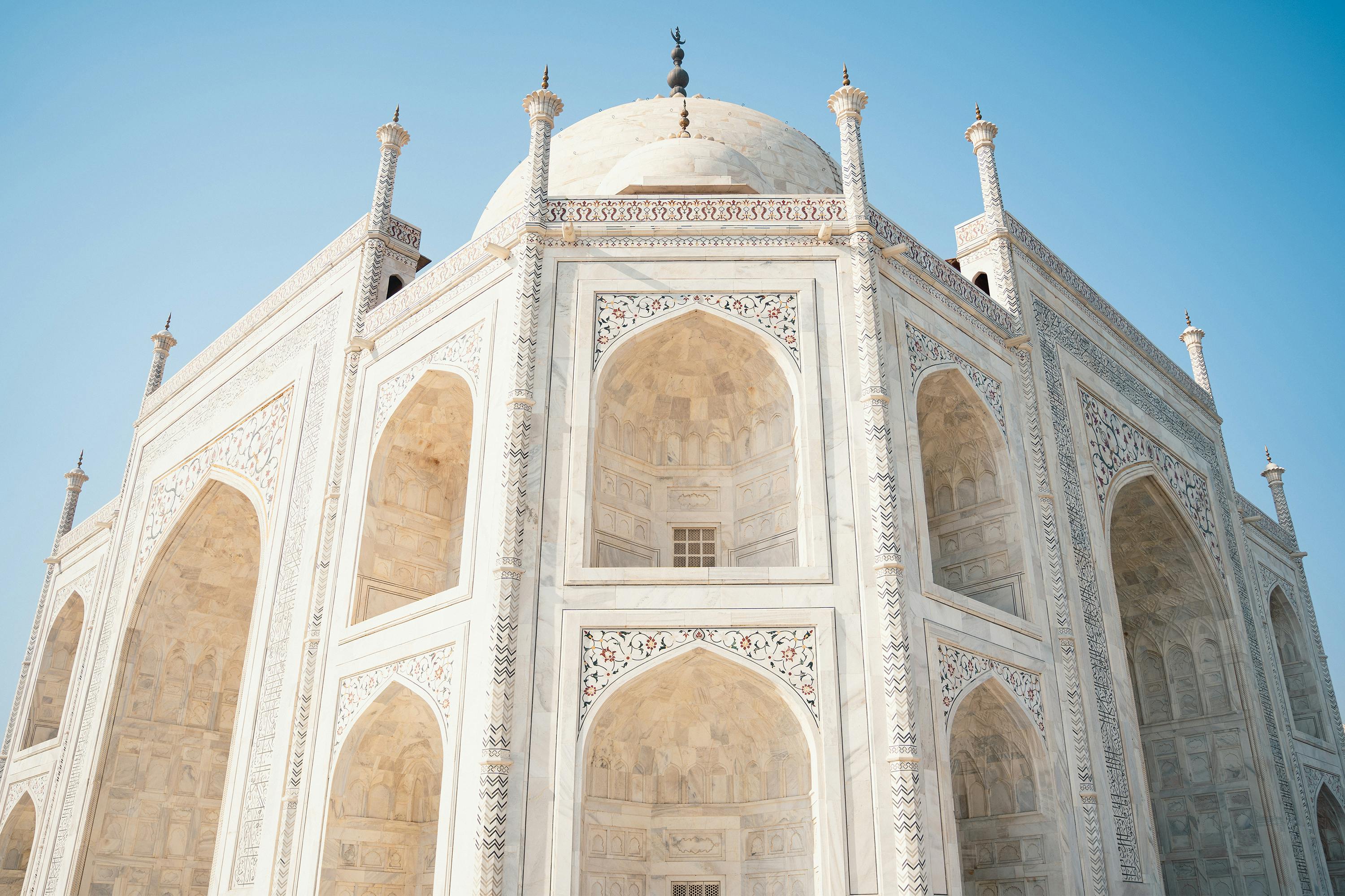Close-up of the stunning architecture of the Taj Mahal on a sunny day in Agra, India.