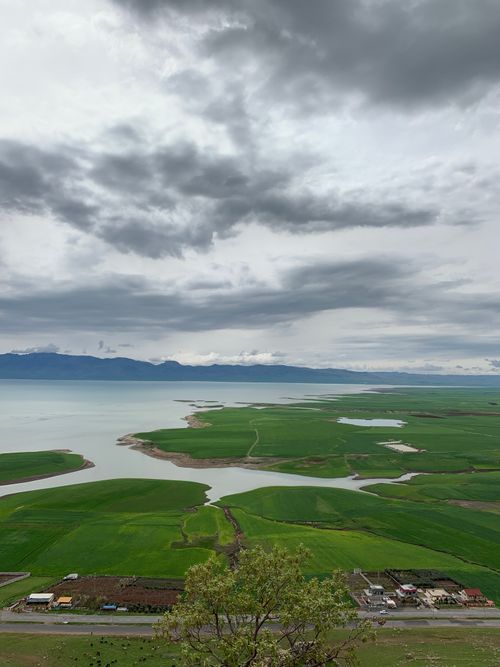 Free Breathtaking view of a lake surrounded by lush green fields under a cloudy sky in Qurago, Sulaymaniyah. Stock Photo