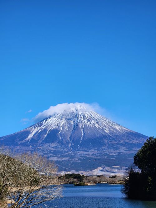 Free A stunning view of snow-capped Mount Fuji under a bright blue sky during winter. Stock Photo