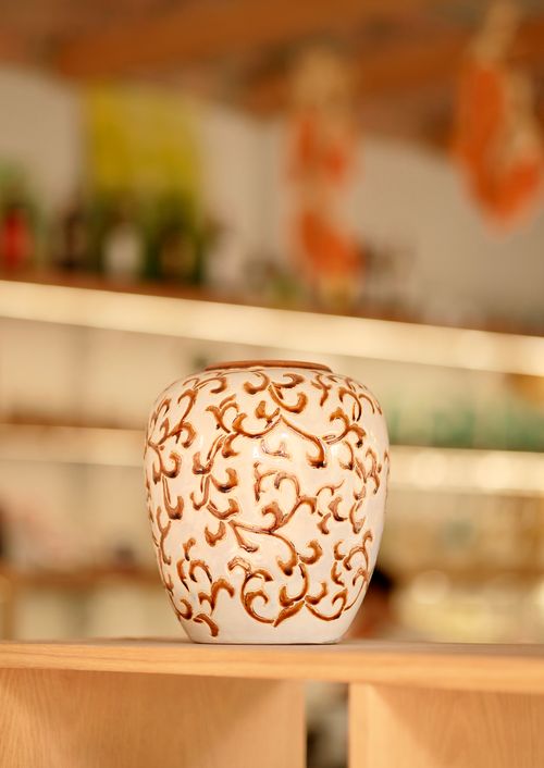 Free Ornate ceramic vase with a vintage design on a wooden shelf, perfect for home decor. Stock Photo