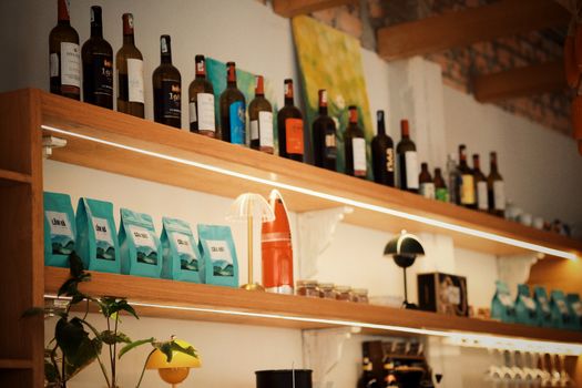 Warm and inviting cafe shelf with wine bottles and coffee bags, creating a cozy atmosphere.