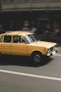 一辆经典的黄色汽车在第比利斯的城市道路上飞驰，尽显速度与复古魅力