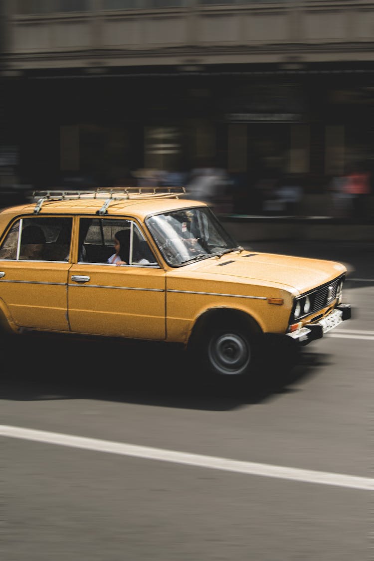 Yellow Sedan Driving On Road