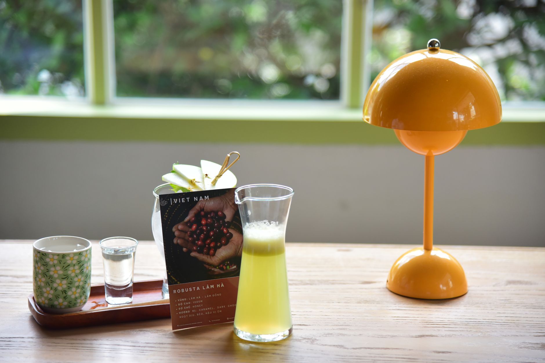 A vibrant café table setting with coffee, juice, and decorative lamp.