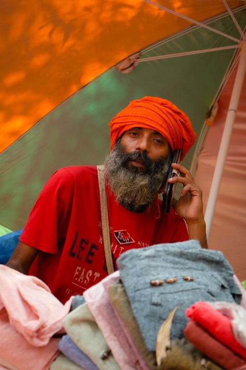 Free Street vendor in Santiniketan, India wearing a vibrant turban, surrounded by fabrics. Stock Photo