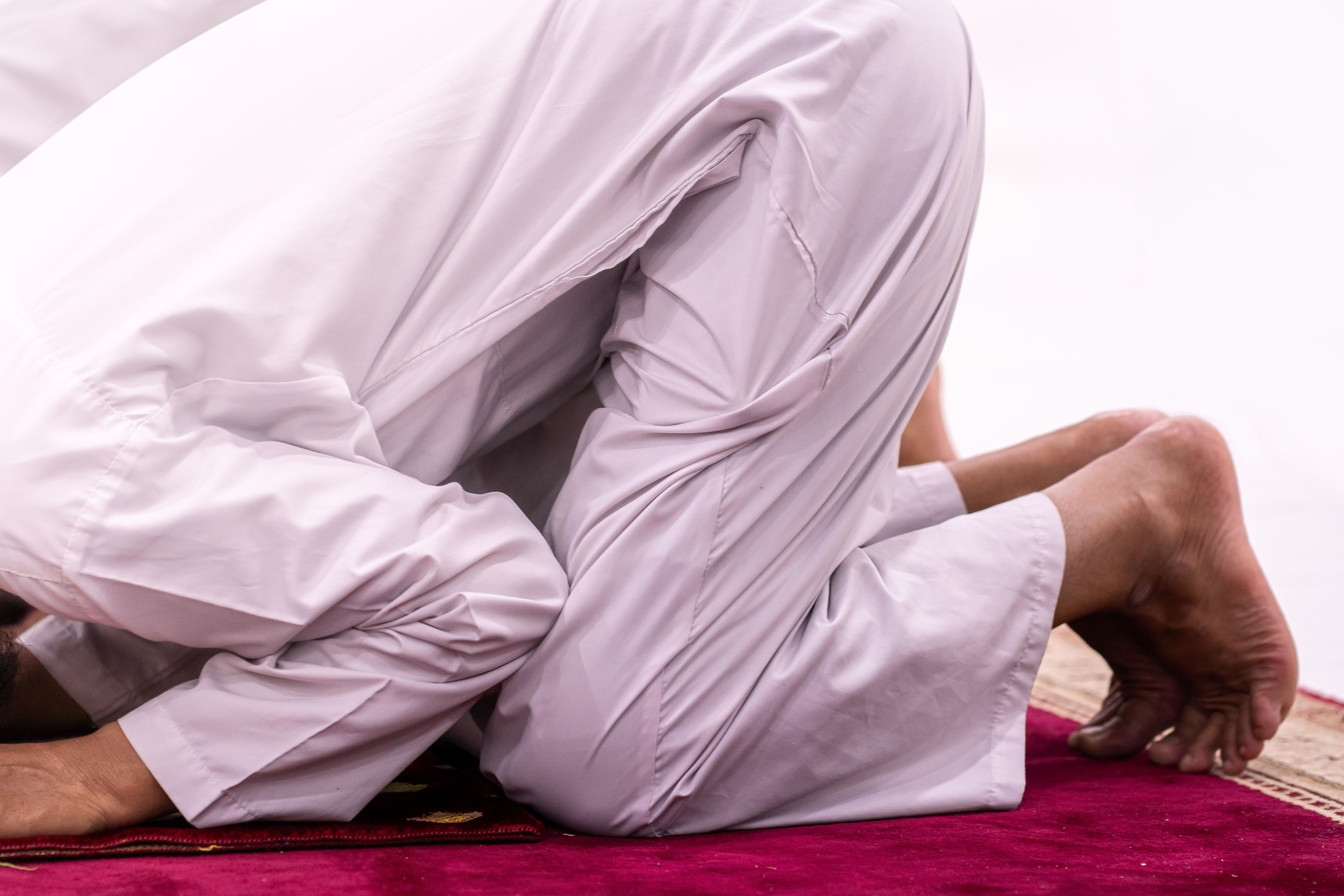 Close-up of a Muslim person in prayer position on a red carpet in Sulawesi Selatan, Indonesia.