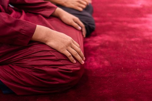 Free Muslim man in traditional attire praying indoors on a red carpet, focusing on spirituality and tradition. Stock Photo