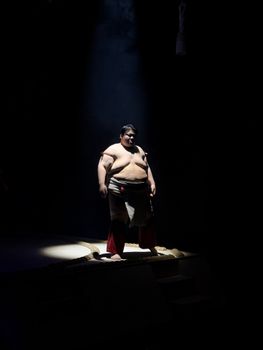 Powerful spotlight photograph of a sumo wrestler in a traditional Japanese sumo arena in Osaka.