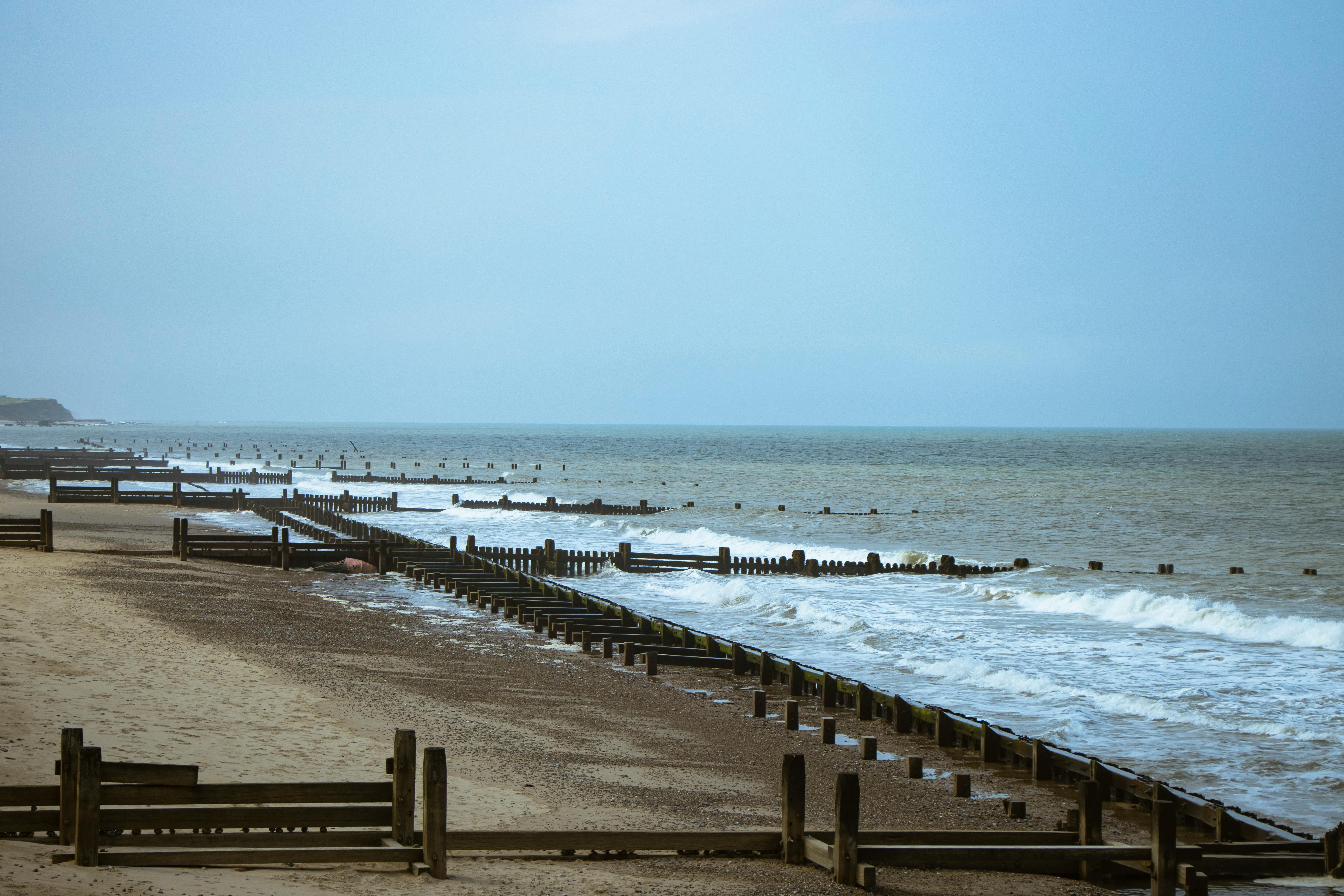 A serene coastal scene featuring wooden groynes by the sea in England on a moody day.