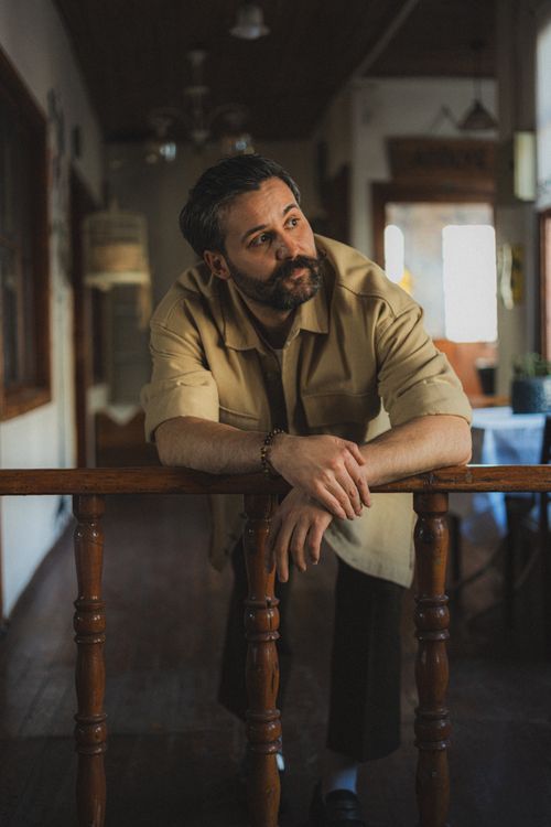 Free Portrait of a bearded man leaning on a wooden railing inside a cozy room. Stock Photo