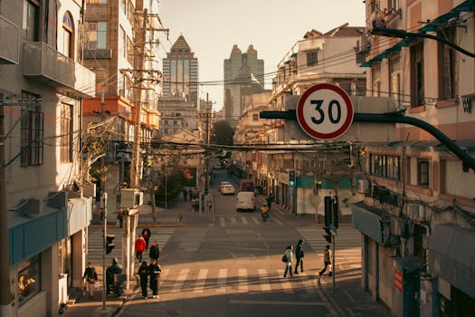 A bustling city street intersection with pedestrians and vehicles under a speed limit sign during daylight.