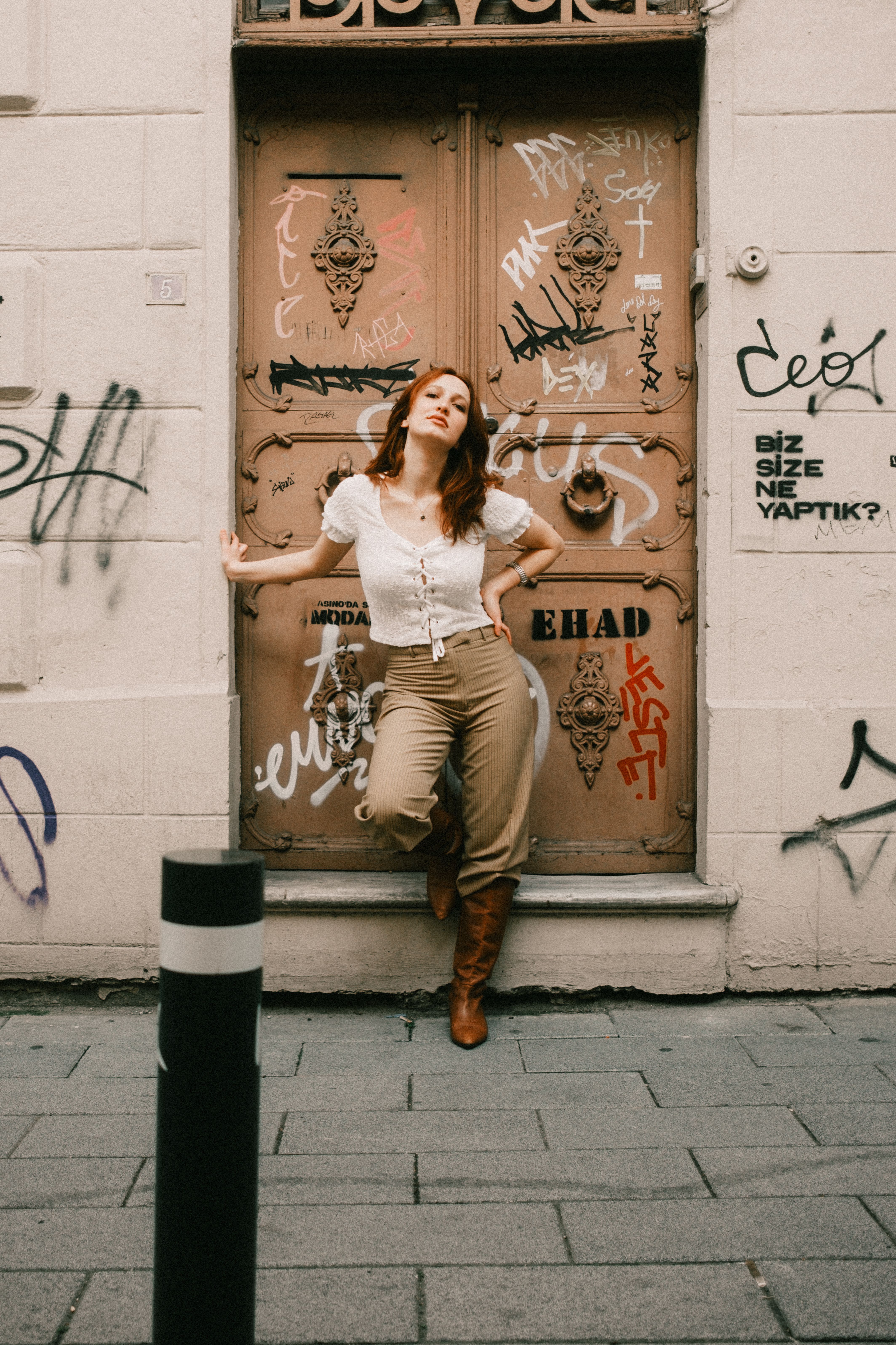 Stylish woman poses with graffiti backdrop, urban fashion vibe.
