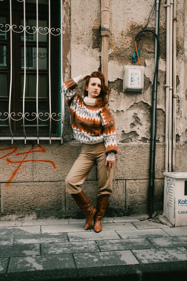 Woman wearing a caramel cowl-neck sweater with grey jeans