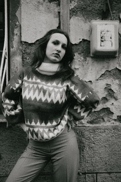 Free A classic black and white portrait of a woman in a patterned sweater, posing against a textured wall. Stock Photo