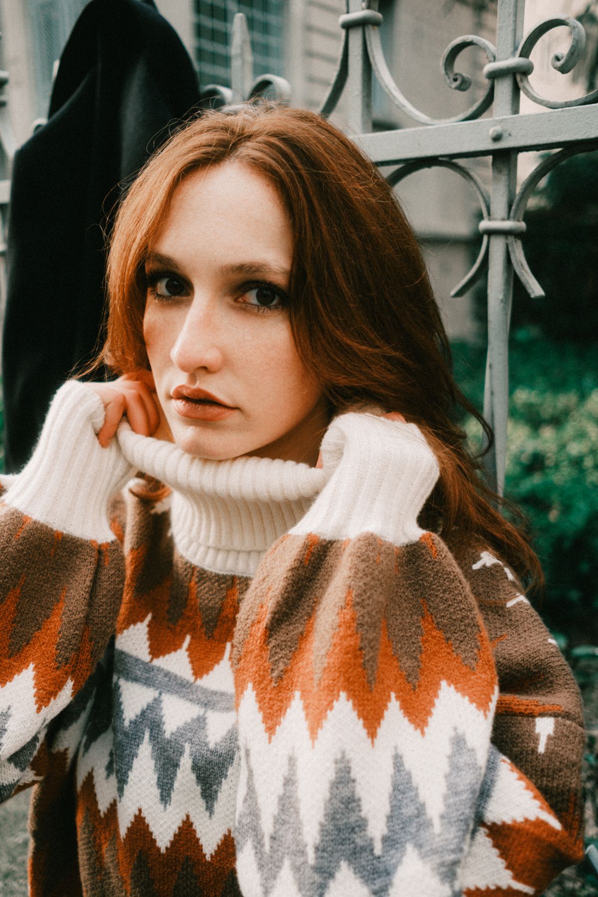 Portrait of a young woman in a patterned sweater outdoors, exuding a warm and cozy mood.