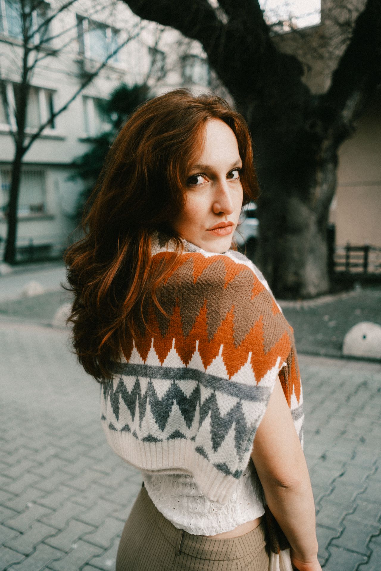 Woman wearing a colorful geometric knit poncho as a shawl wrap on a city street