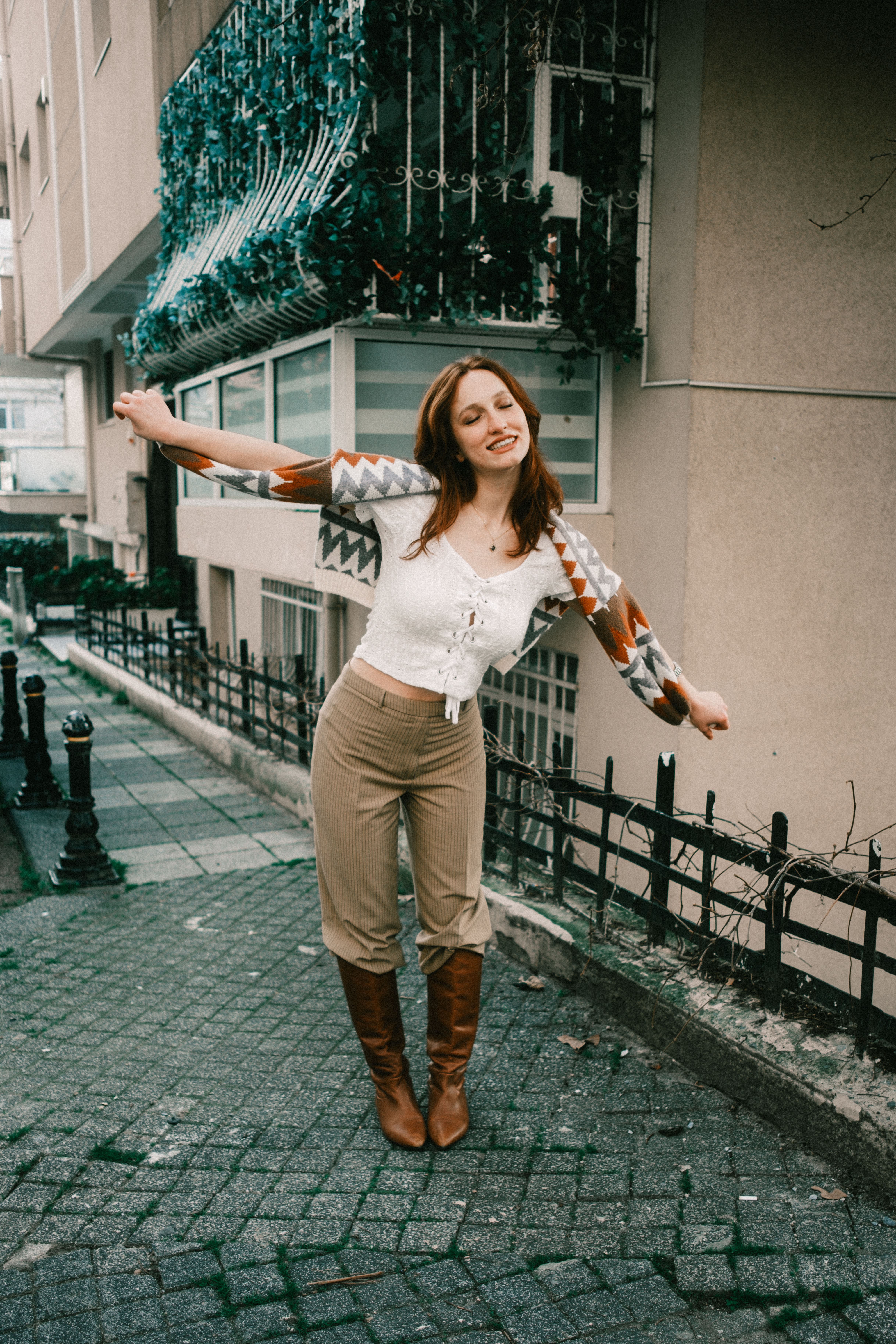 Happy woman with outstretched arms on an urban street, expressing joy.