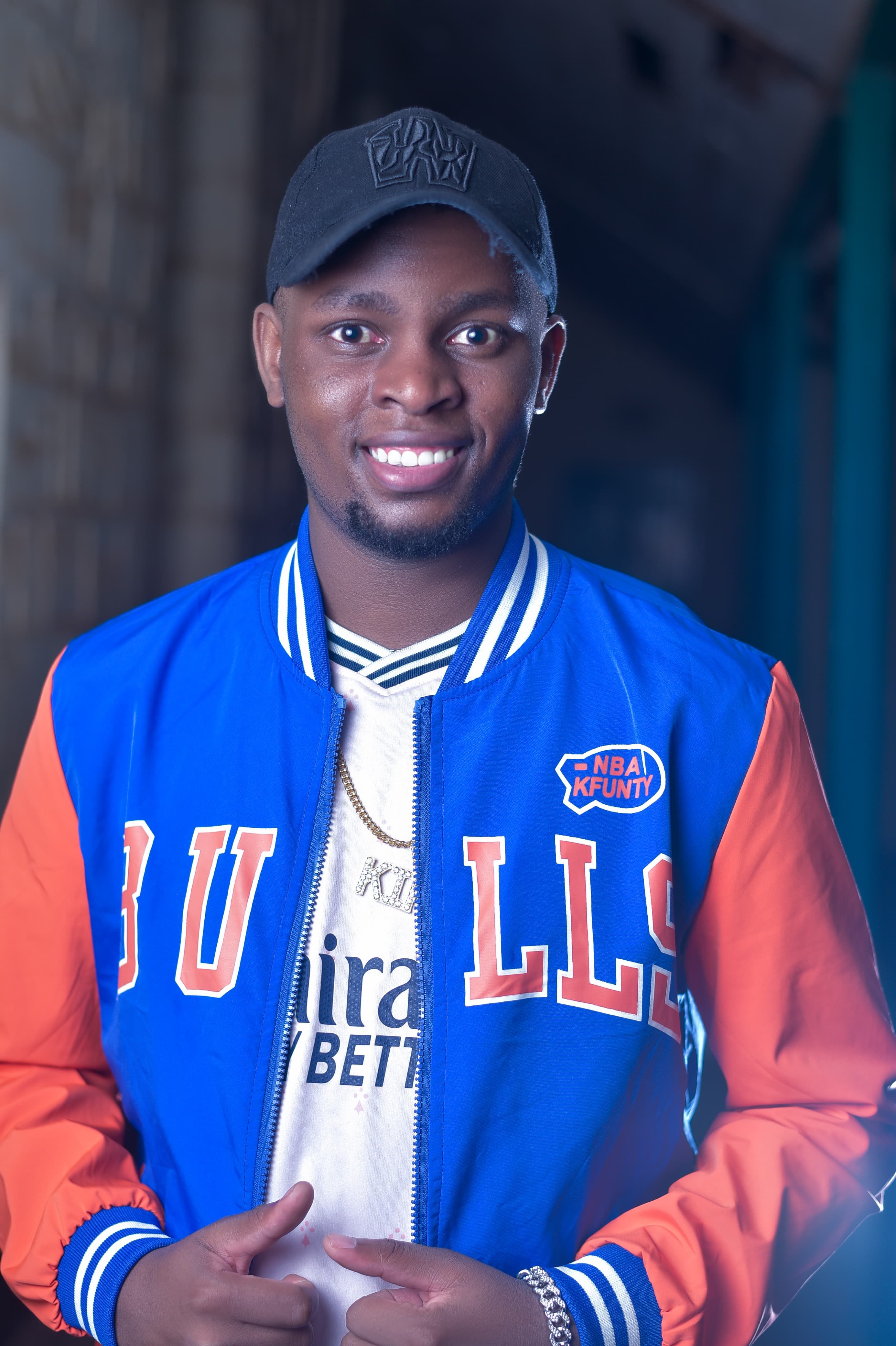 A cheerful young adult wearing a vibrant jacket outdoors in Machakos, Kenya.