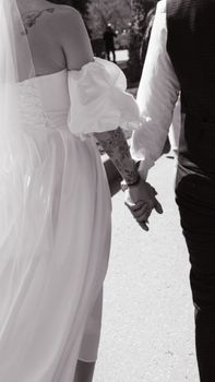 A romantic black and white photo of a bride and groom holding hands outdoors, exuding love and unity.