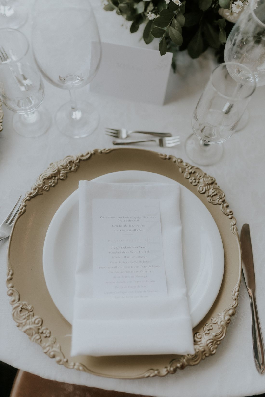 Elegant place setting with a gold charger plate and menu card