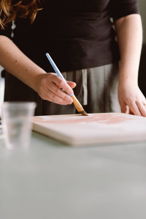 Free A woman artist engaged in painting, focusing on her creative process in a sunlit studio. Stock Photo