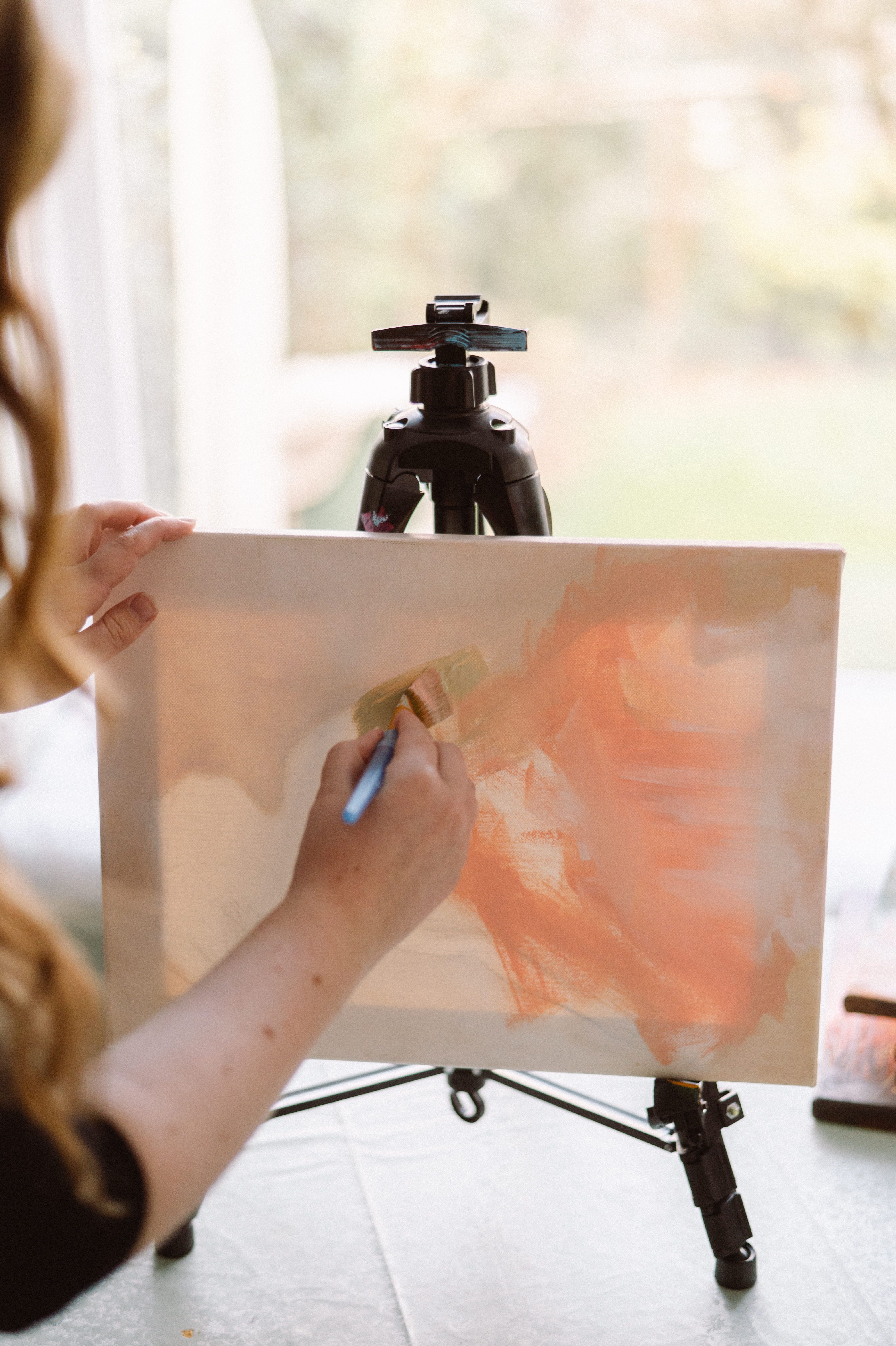 A female artist painting with natural light in a home studio