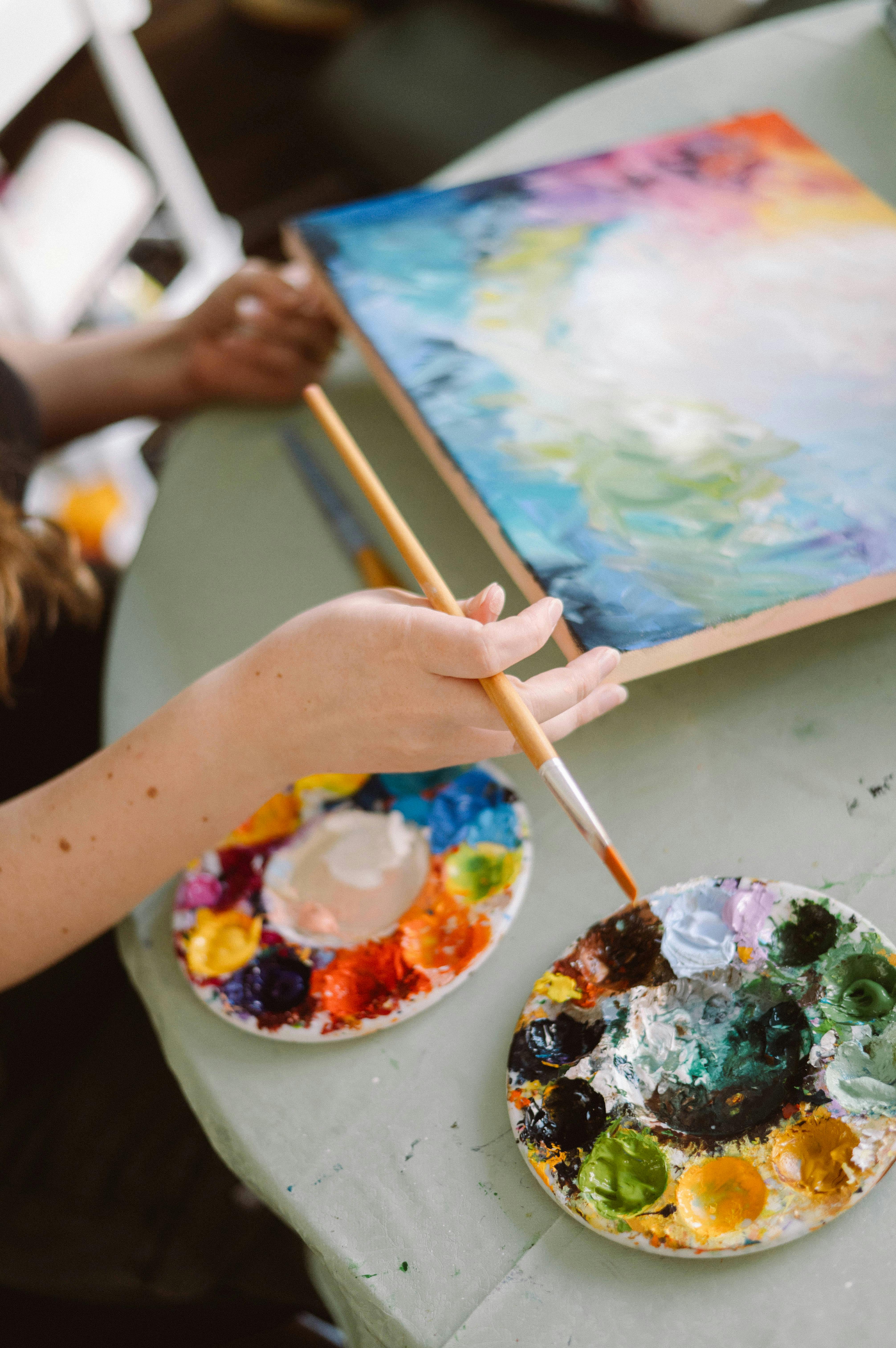 Female artist paints vibrant canvas under natural light.