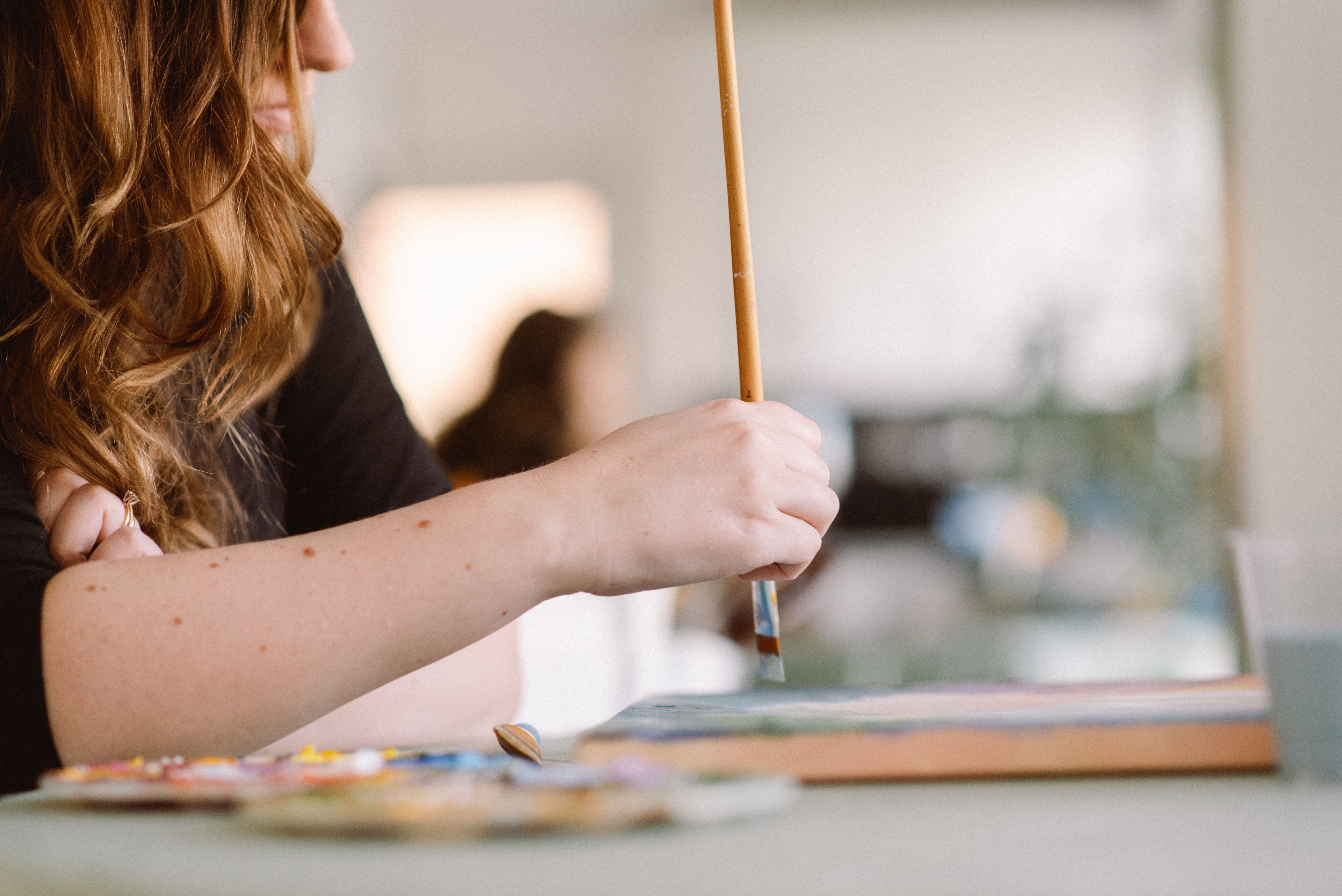 gratis Een vrouwelijke kunstenaar schildert op doek in een zonnig, zonnig atelier en toont haar creatieve proces. Stockfoto
