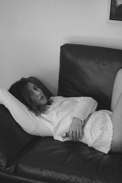 Free A serene black and white portrait of a woman relaxing on a sofa, evoking calm and introspection. Stock Photo
