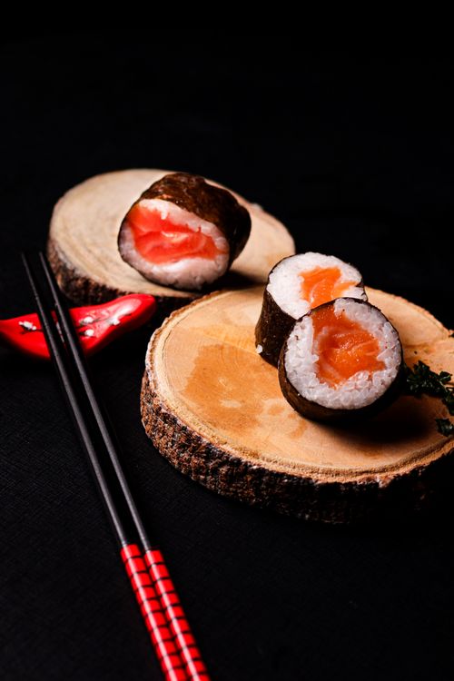 Free Fresh salmon sushi rolls elegantly presented on wooden slices with chopsticks. Stock Photo