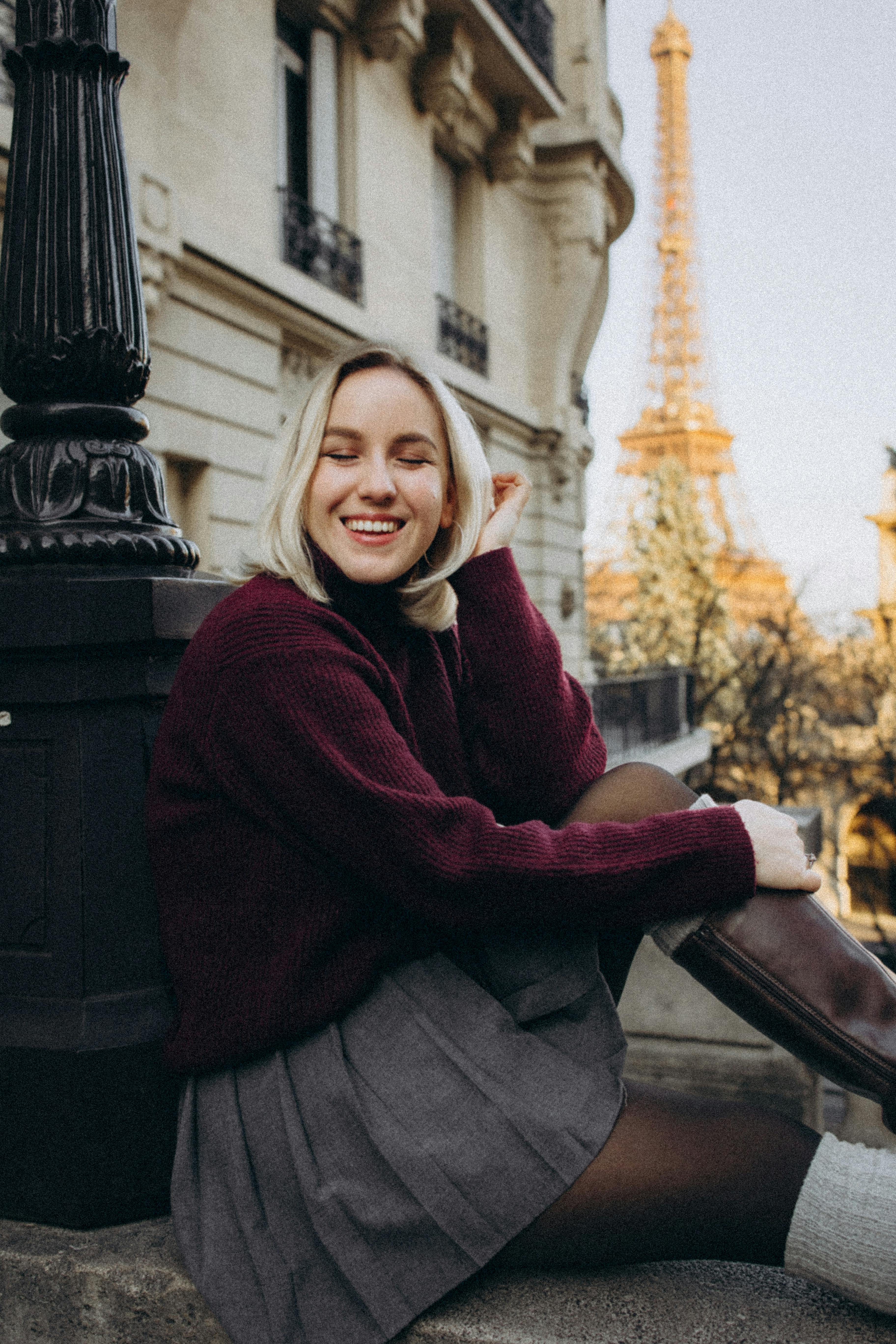 Smiling woman enjoying a sunny day with the Eiffel Tower in the background.