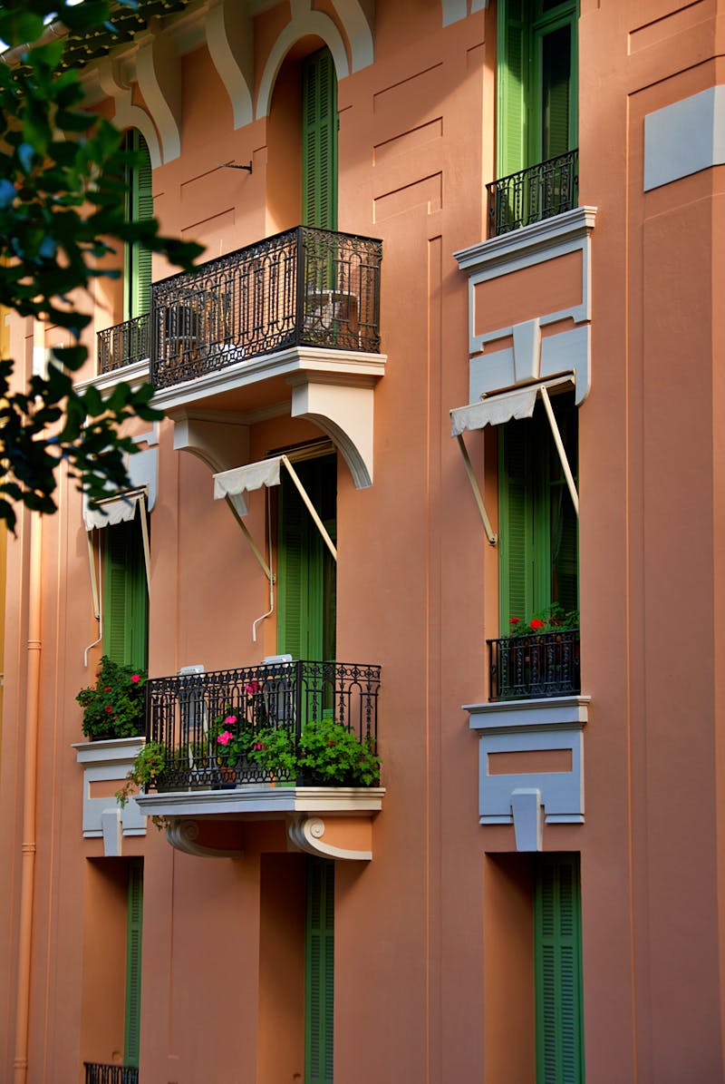 Mediterranean apartment building with traditional enclosed balconies and limestone facade in summer sunlight