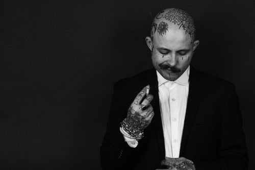 Free A monochrome portrait of a bald, tattooed man in a suit, exuding a dramatic and artistic vibe. Stock Photo