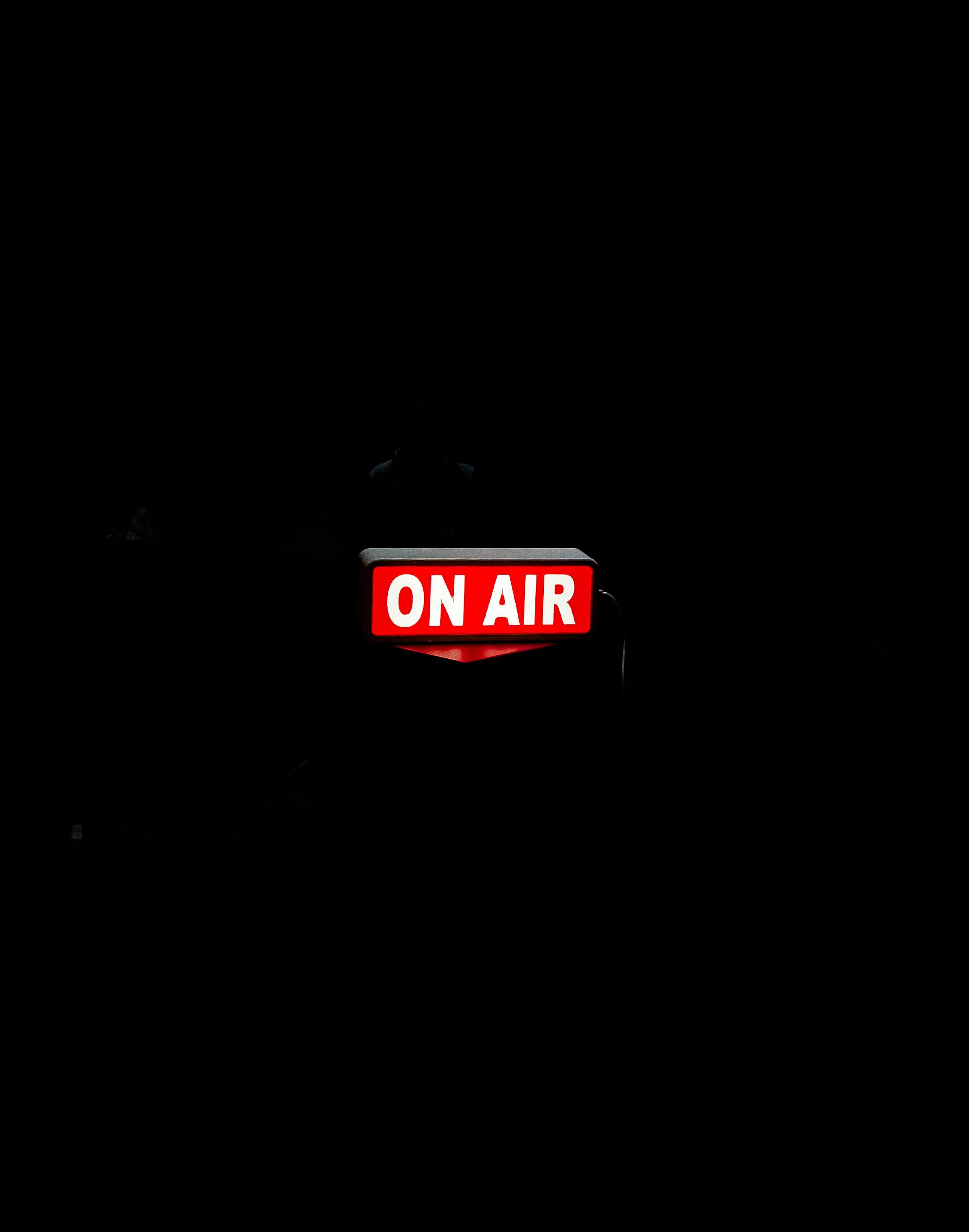 On Air sign glowing in a dark studio