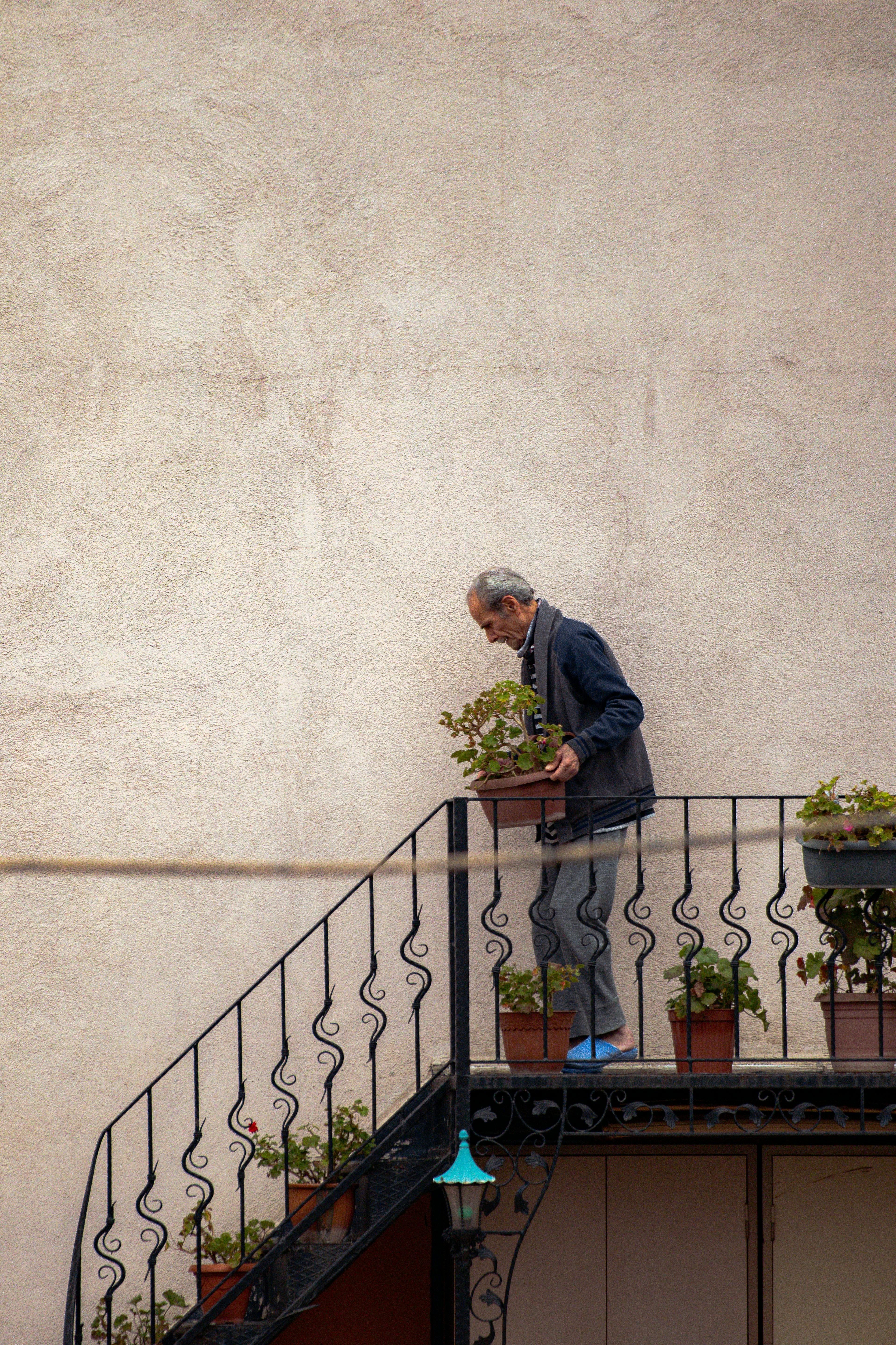 Senior man tending potted plants on an outdoor staircase in Bursa, Türkiye.