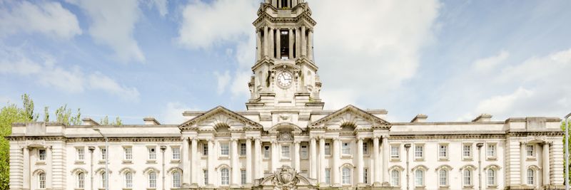 Front view of the iconic Stockport Town Hall with a clear blue sky backdrop.