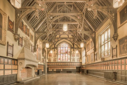 A beautiful historic hall in England featuring ornate timber architecture and stained glass windows.