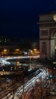 Captivating night scene of Arc de Triomphe in Paris with vibrant light trails.