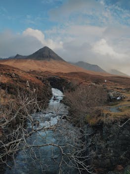 A tranquil view of mountains and river in Scotland's Highland region with dramatic skies.