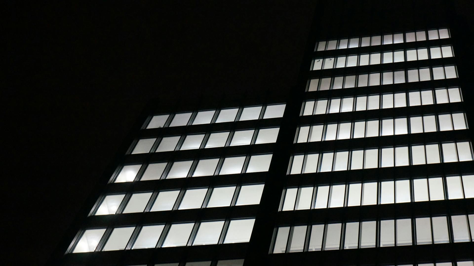 Illuminated skyscraper facade in Greater London at night, showcasing modern urban architecture.