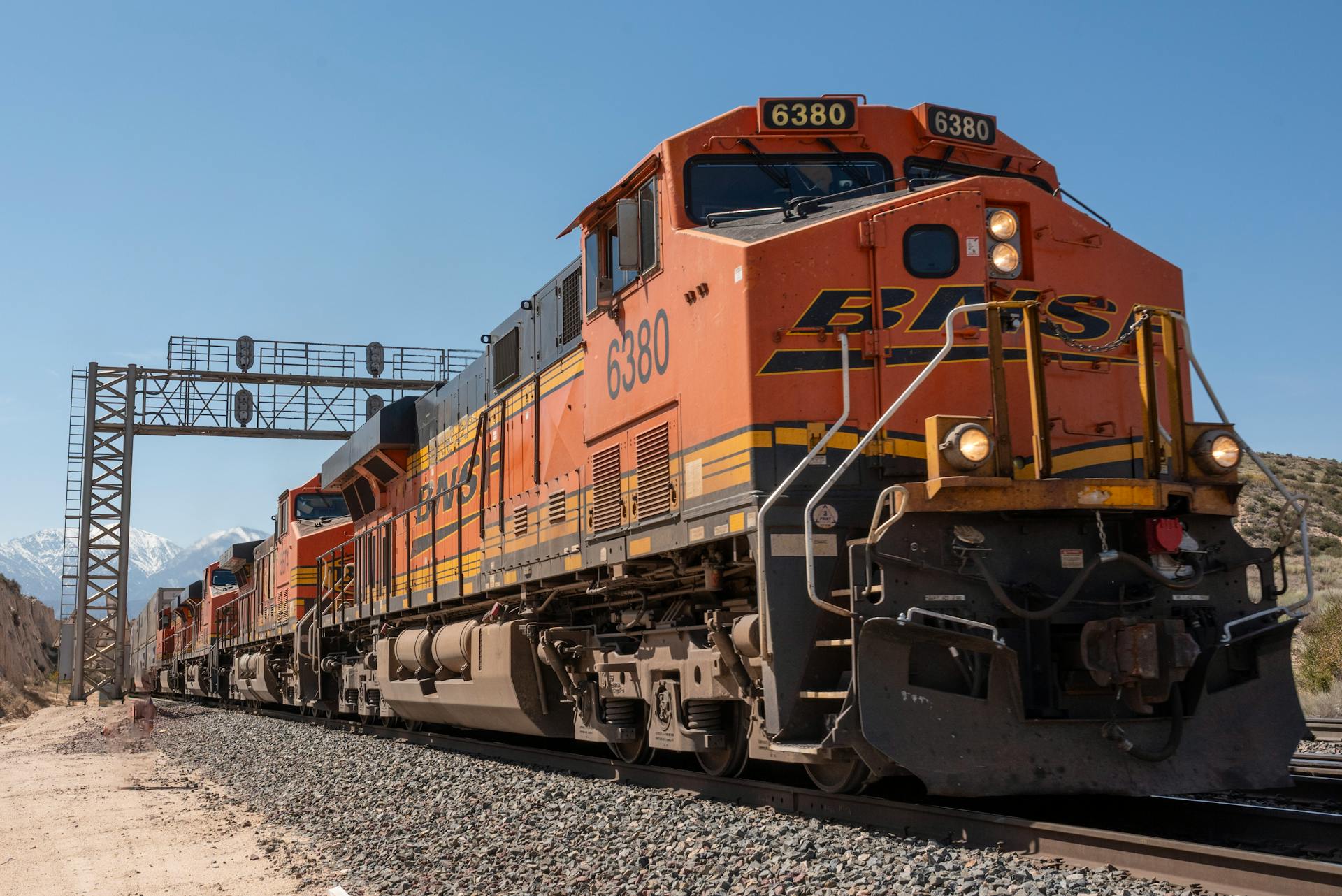 A powerful freight train traveling on tracks with scenic California mountains in the background.